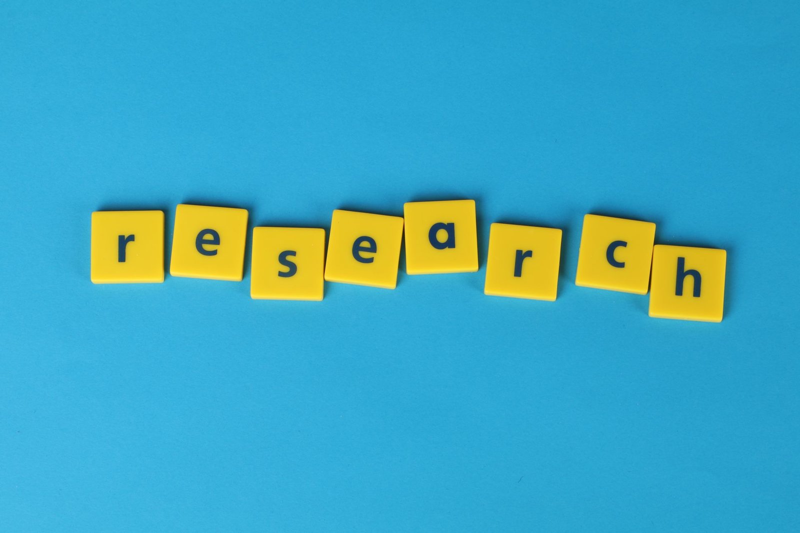 Yellow letter tiles spelling “research” on a blue background