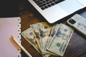 Laptop, smartphone, notebook, and cash representing ways to make money blogging