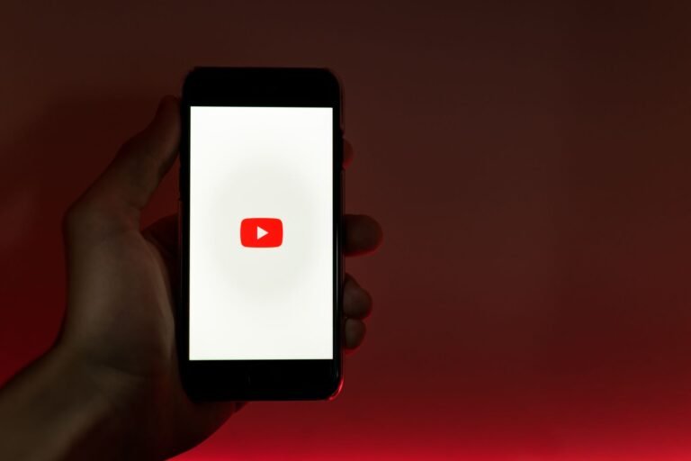Hand holding a smartphone displaying the YouTube logo